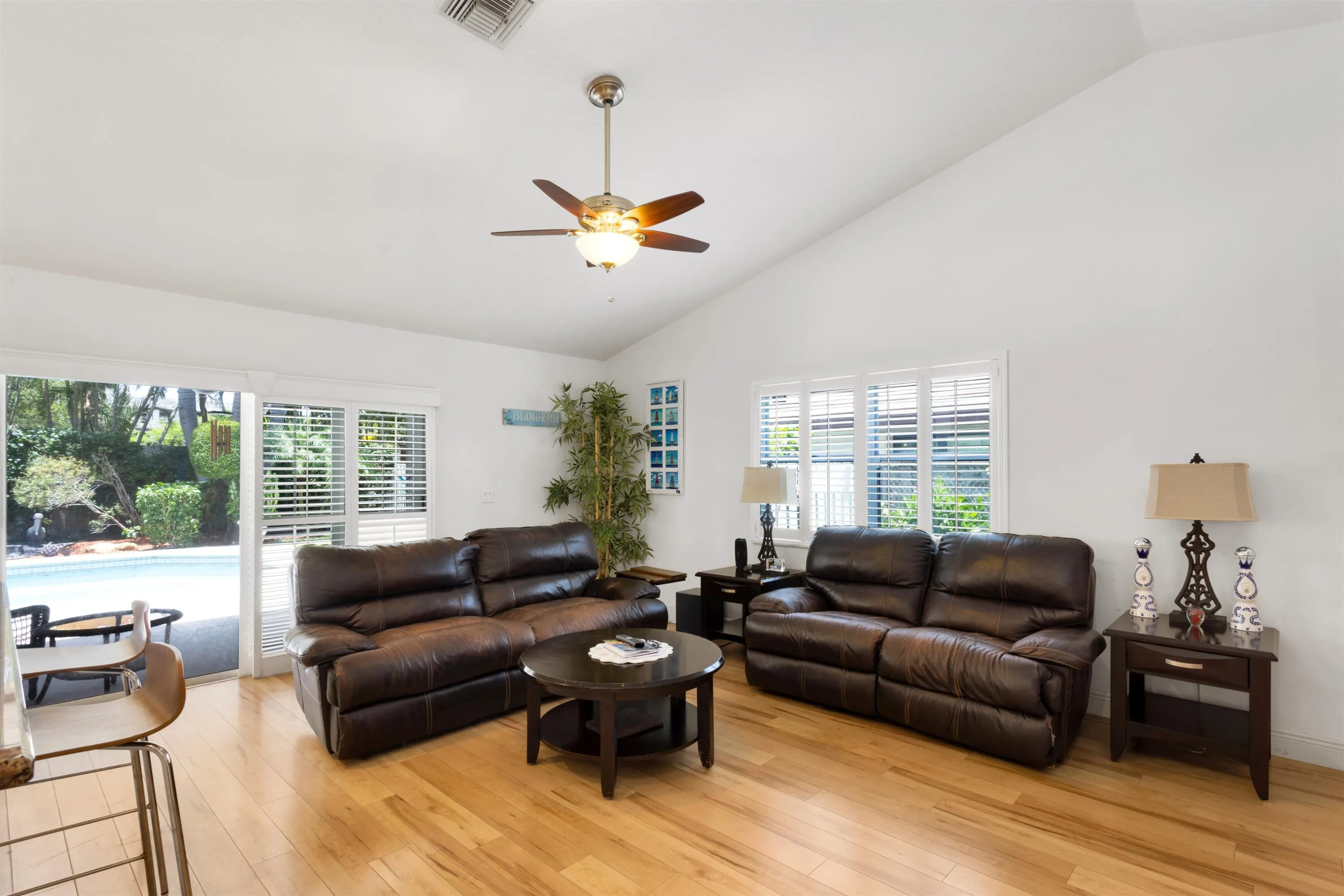 second living area off kitchen leading to backyard with vaulted ceilings