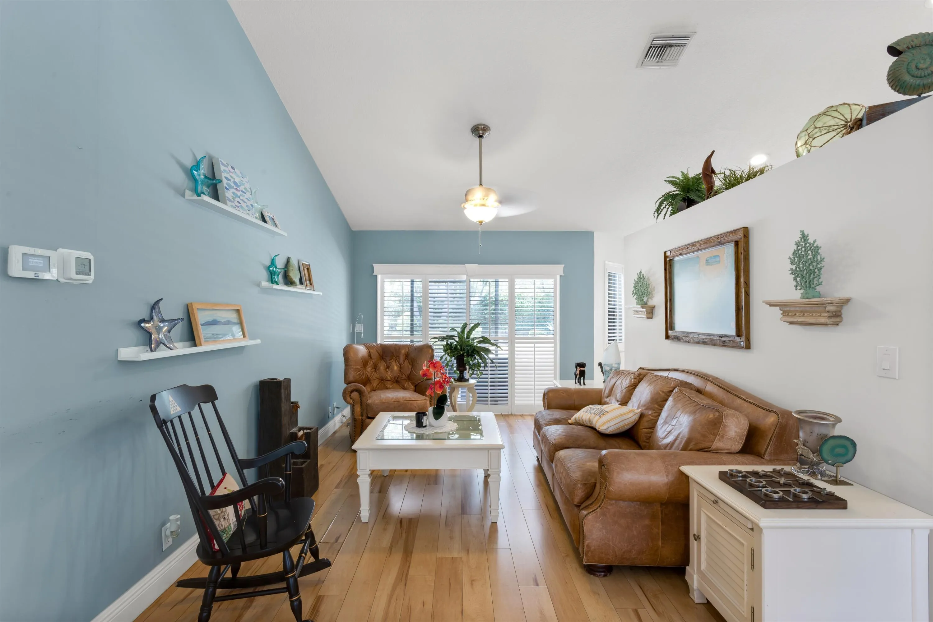 Front living area with vaulted ceilings, plantation shutters leading to backyard