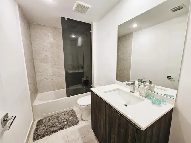 Modern bathroom featuring a wood-finish vanity with an integrated sink and white countertop