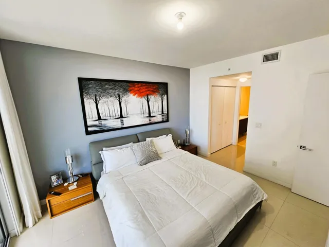 Spacious room featuring light-toned tile flooring, light gray wall accents, and an overhead light fixture