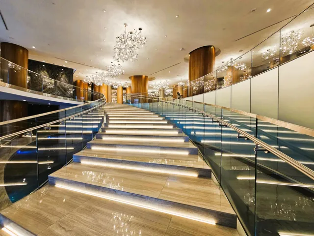 Grand staircase featuring illuminated risers and natural stone treads