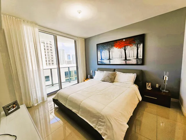 Spacious sleeping area featuring large format tile flooring and a full-height sliding glass door