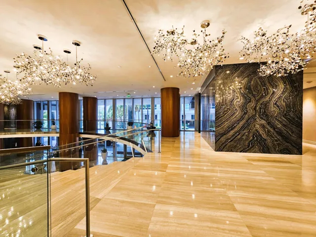 Lobby featuring large-format tile flooring, multiple contemporary chandeliers, and a natural stone accent wall