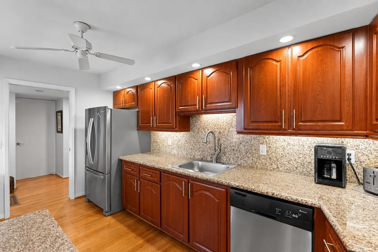 The kitchen offers abundant cherry wood cabinetry, granite countertops with a full granite backsplash, stainless steel appliances, recessed lighting, and generous counter space for meal preparation.