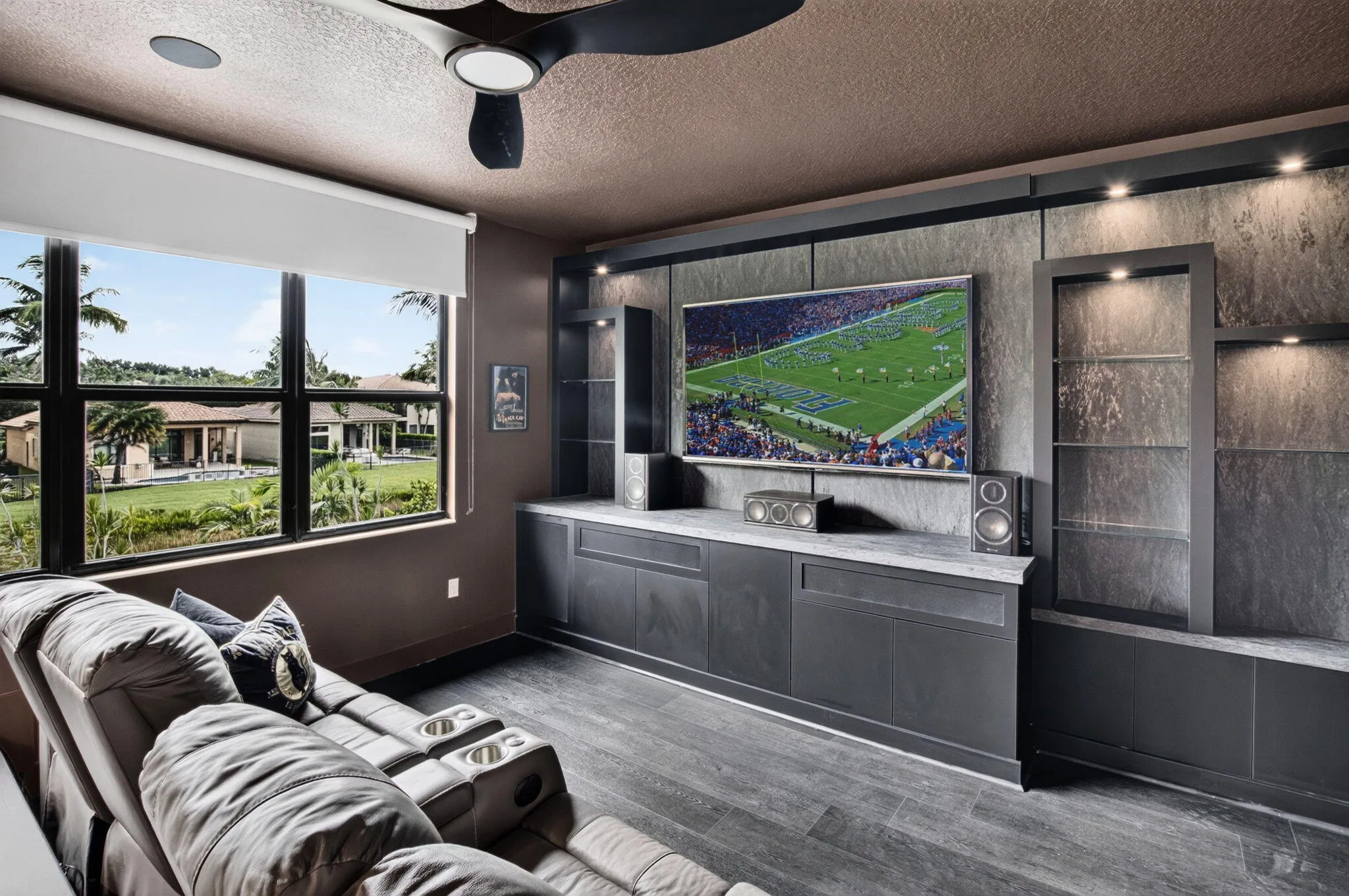Custom built-in media console with stone-finish accent wall, integrated display shelving, and recessed lighting