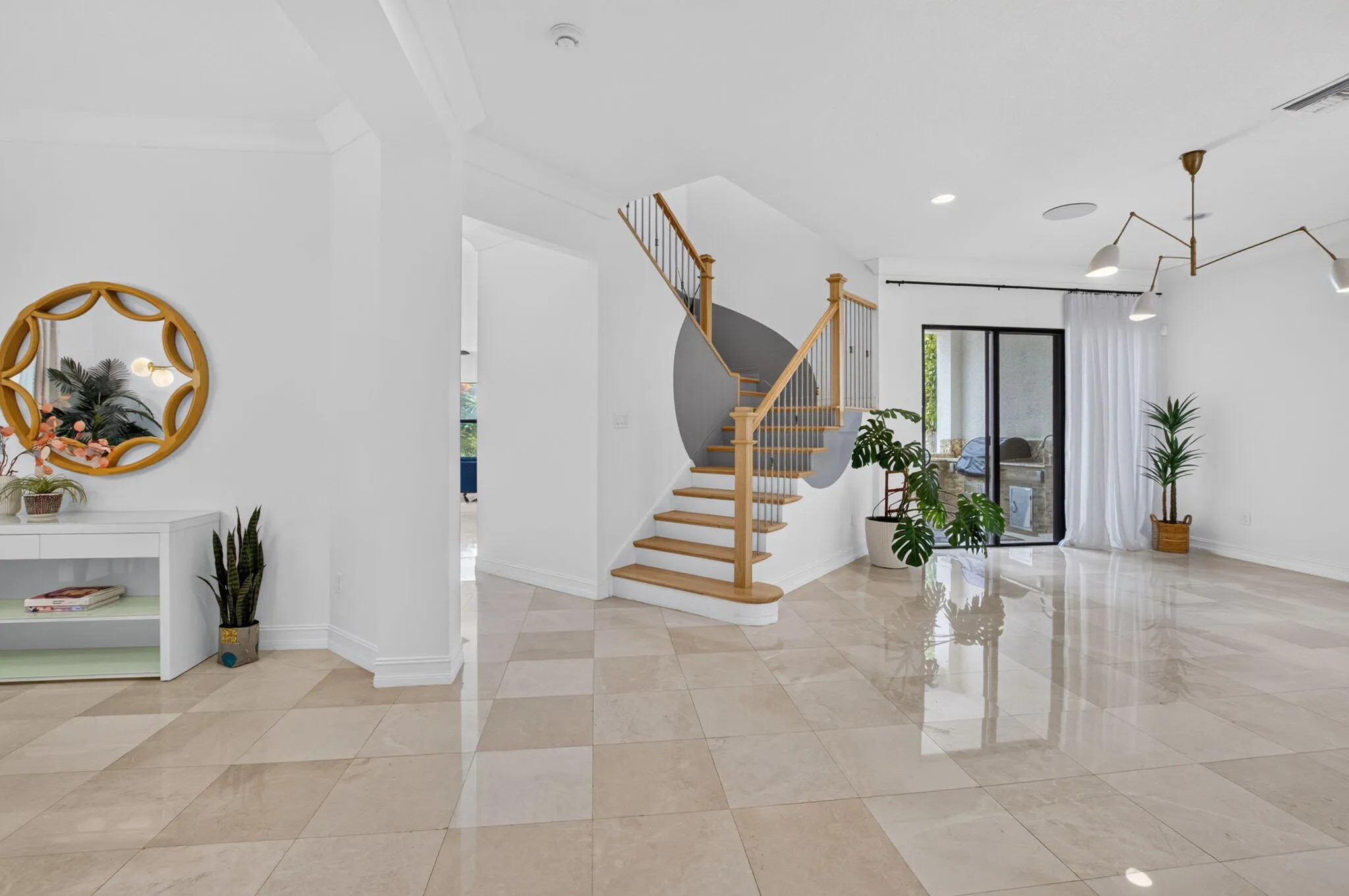 Bright entry foyer featuring diamond-patterned tile flooring and a central wooden staircase with black metal balusters
