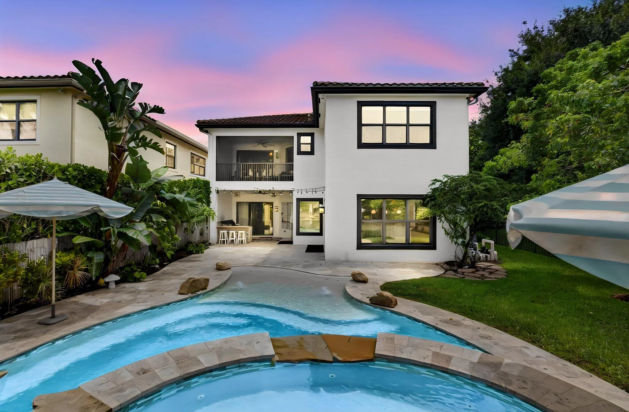 Backyard oasis featuring a freeform swimming pool, expansive paved patio, and a built-in outdoor kitchen
