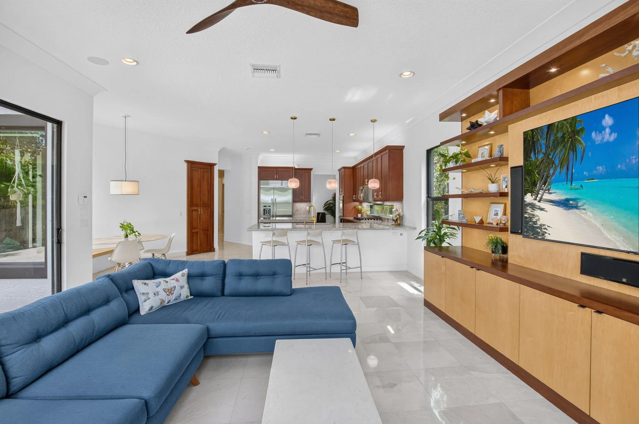 Open-concept living space with light-toned tile flooring, recessed lighting, a ceiling fan, and a built-in media center with shelving and lower cabinetry