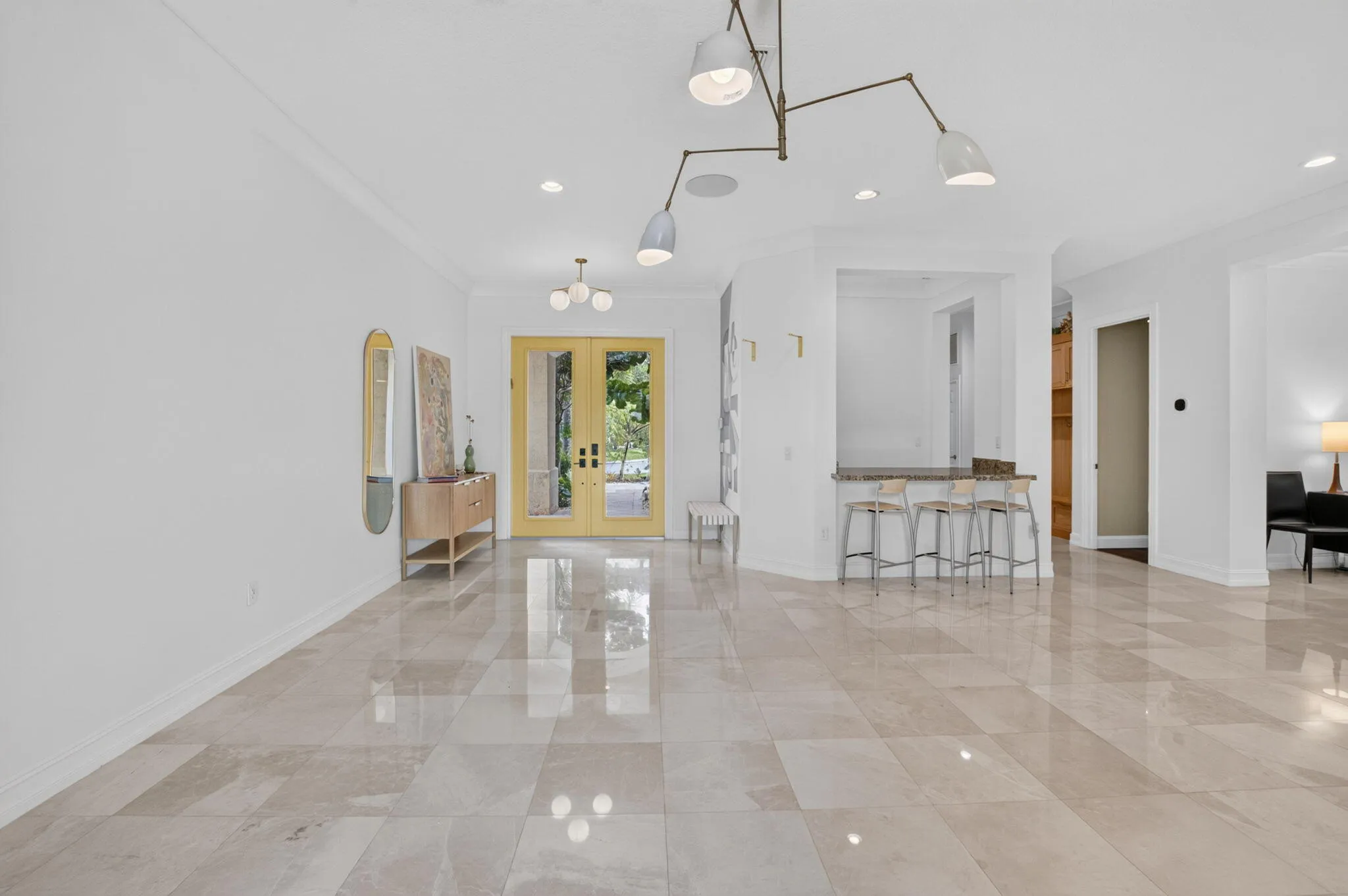 Spacious entry foyer featuring large format tile flooring, a built-in wet bar with seating, recessed lighting, and a contemporary ceiling light fixture