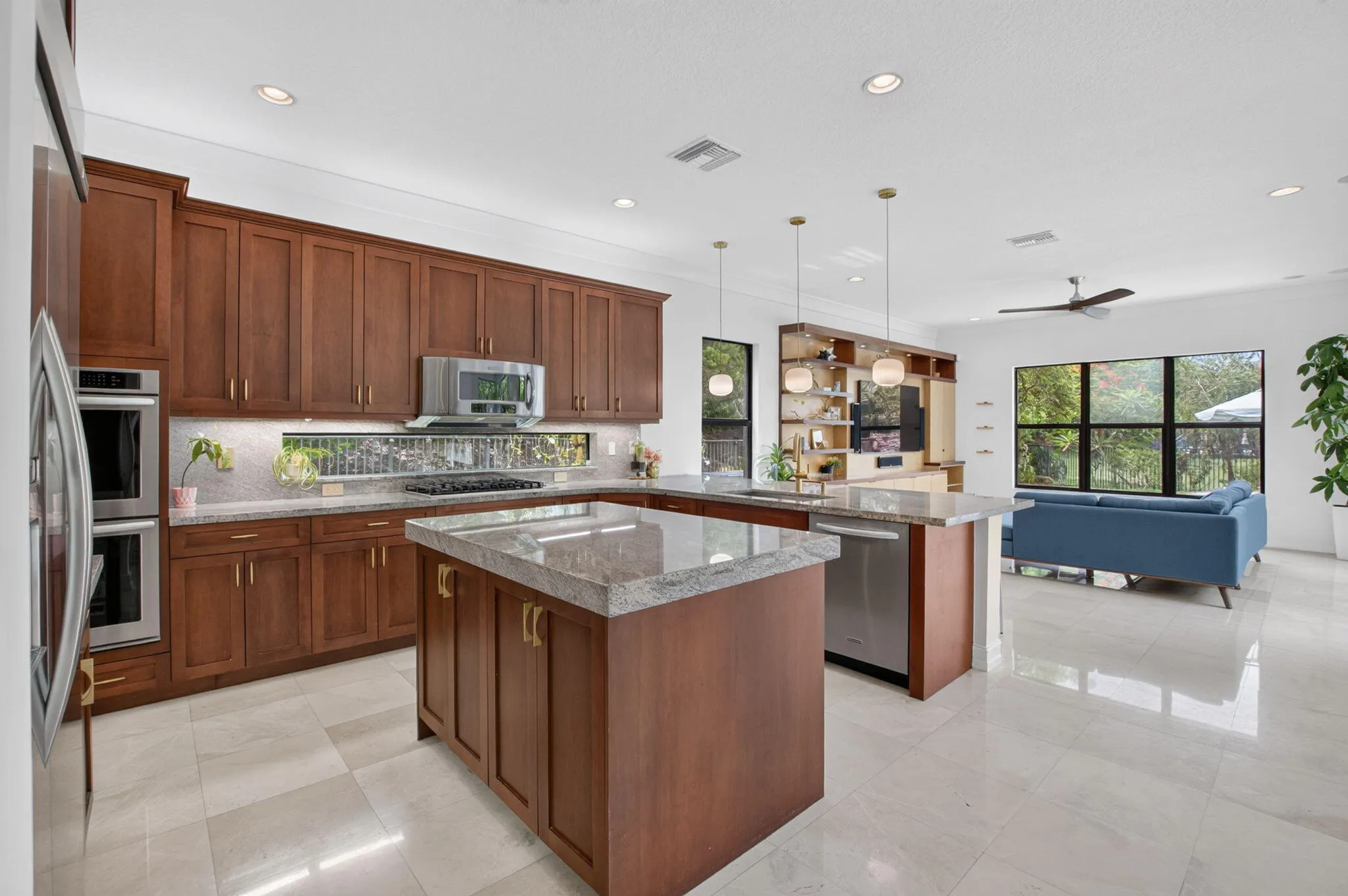 Gourmet kitchen featuring wood cabinetry, light-toned countertops, and stainless steel appliances, including double wall ovens