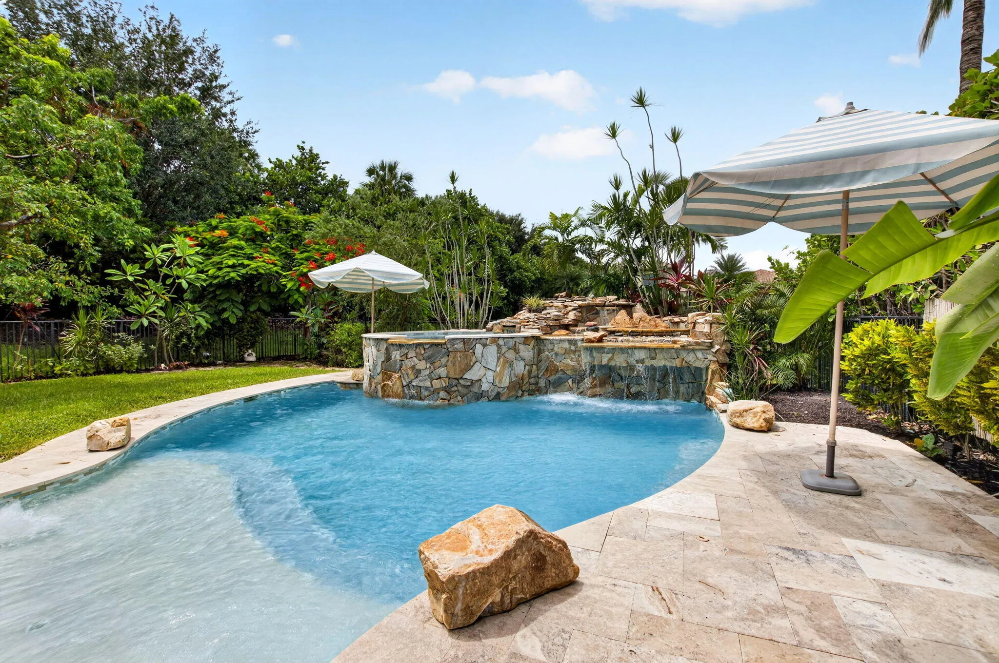Curved swimming pool with a stone waterfall feature and integrated spa
