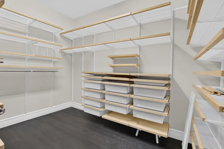 Customizable closet system featuring wood-finish shelving, integrated drawers, hanging rods, and dark wood-finish flooring