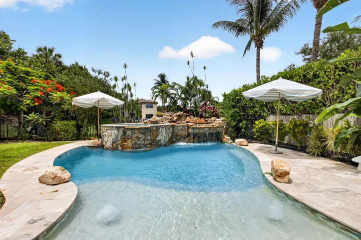 Resort-style pool featuring a rock waterfall and integrated spa