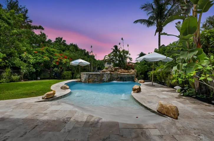 Custom-shaped swimming pool featuring a rock waterfall and integrated fountains