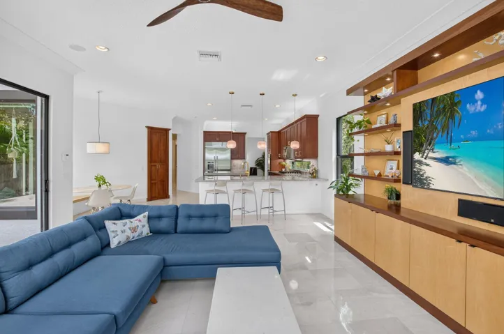 Open-concept living space with light-toned tile flooring, recessed lighting, a ceiling fan, and a built-in media center with shelving and lower cabinetry