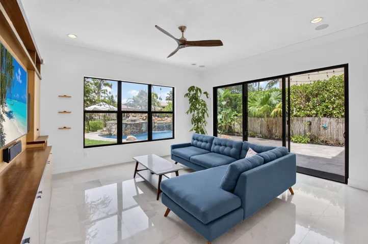Spacious living area featuring polished tile flooring, a dark wood-finish ceiling fan, and recessed lighting