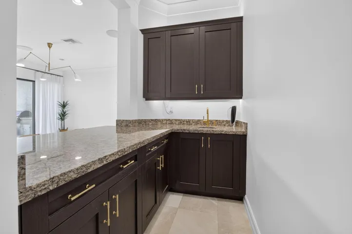 Custom built-in cabinetry with gold-tone hardware, a light-toned patterned countertop, and an undermount sink with a gold-tone faucet