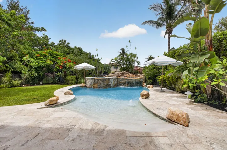 Freeform pool with a rock waterfall feature and integrated sun shelf