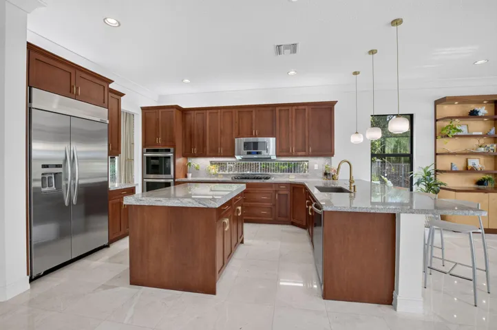 Expansive kitchen featuring wood cabinetry, stainless steel appliances, a center island with countertop seating, and recessed lighting