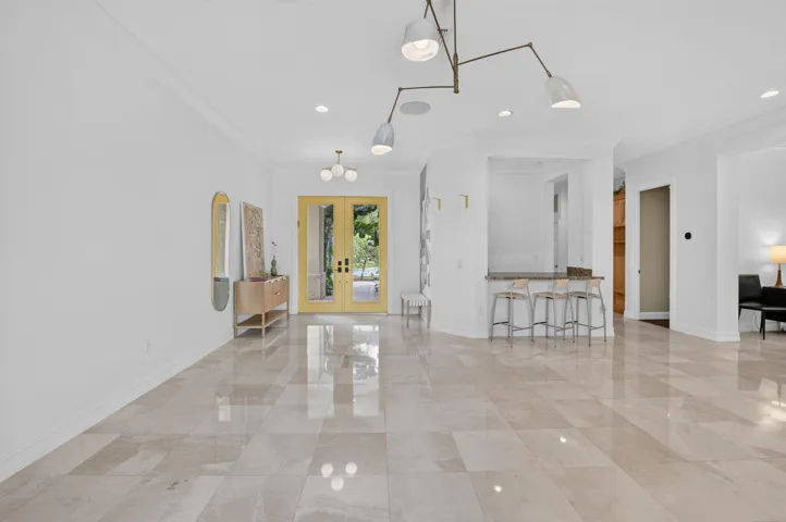 Spacious entry foyer featuring large format tile flooring, a built-in wet bar with seating, recessed lighting, and a contemporary ceiling light fixture