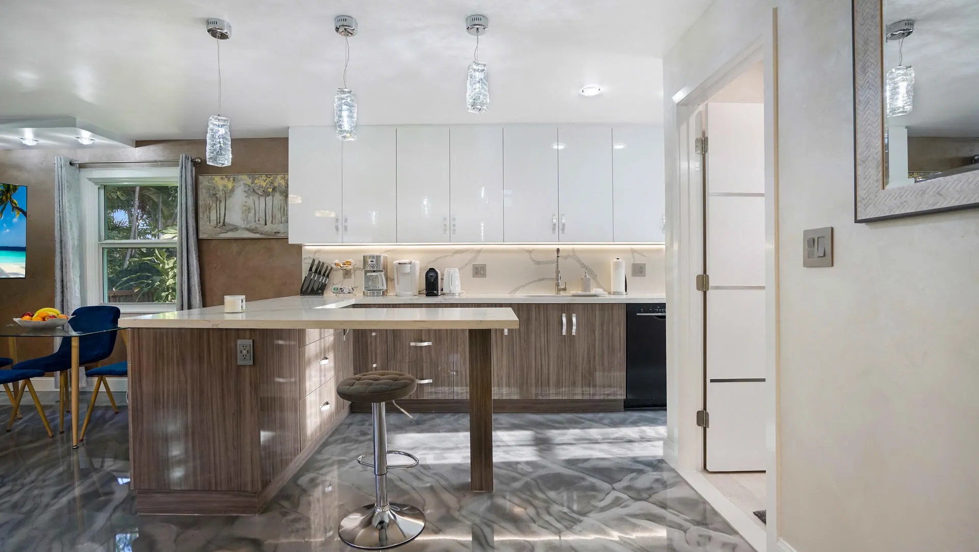 Modern kitchen featuring glossy white upper cabinetry, wood-finish lower cabinetry, and a light-toned countertop