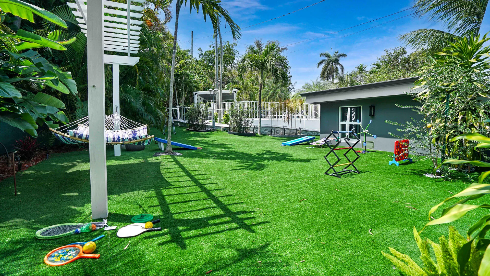 Expansive green lawn with a pergola structure and surrounding tropical foliage