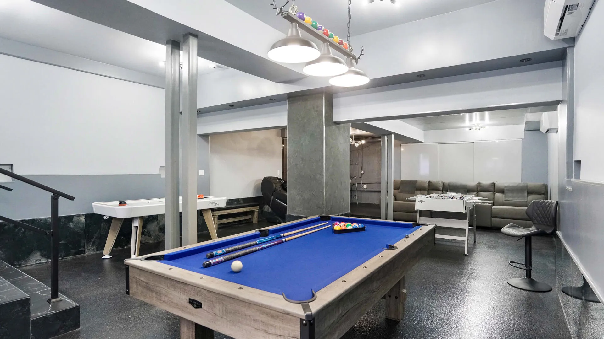 Recreational room featuring a blue felt pool table, dark flooring, and a multi-light fixture