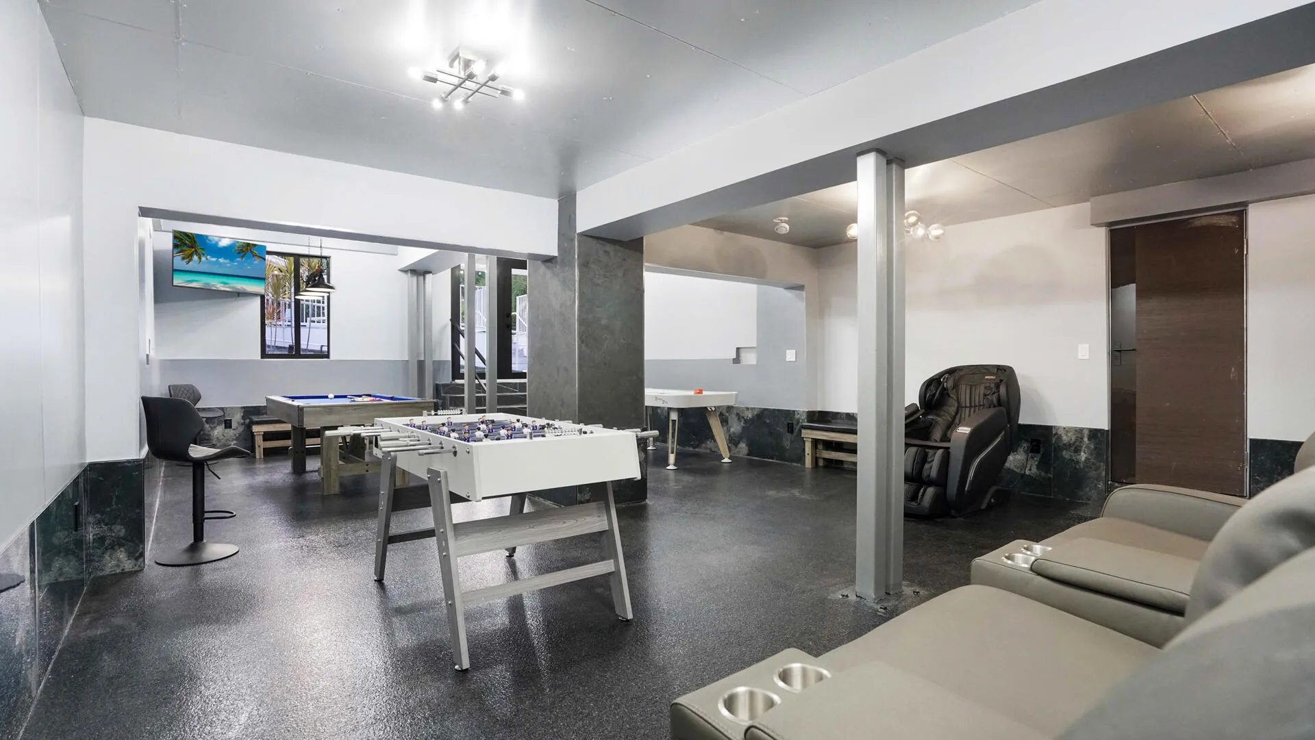 Open recreational area featuring dark flooring, a stone accent wall, and built-in ceiling lighting