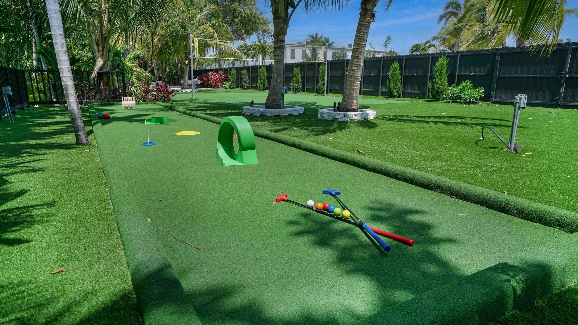 Miniature golf course with artificial turf, bordered by mature palm trees and lush green landscaping