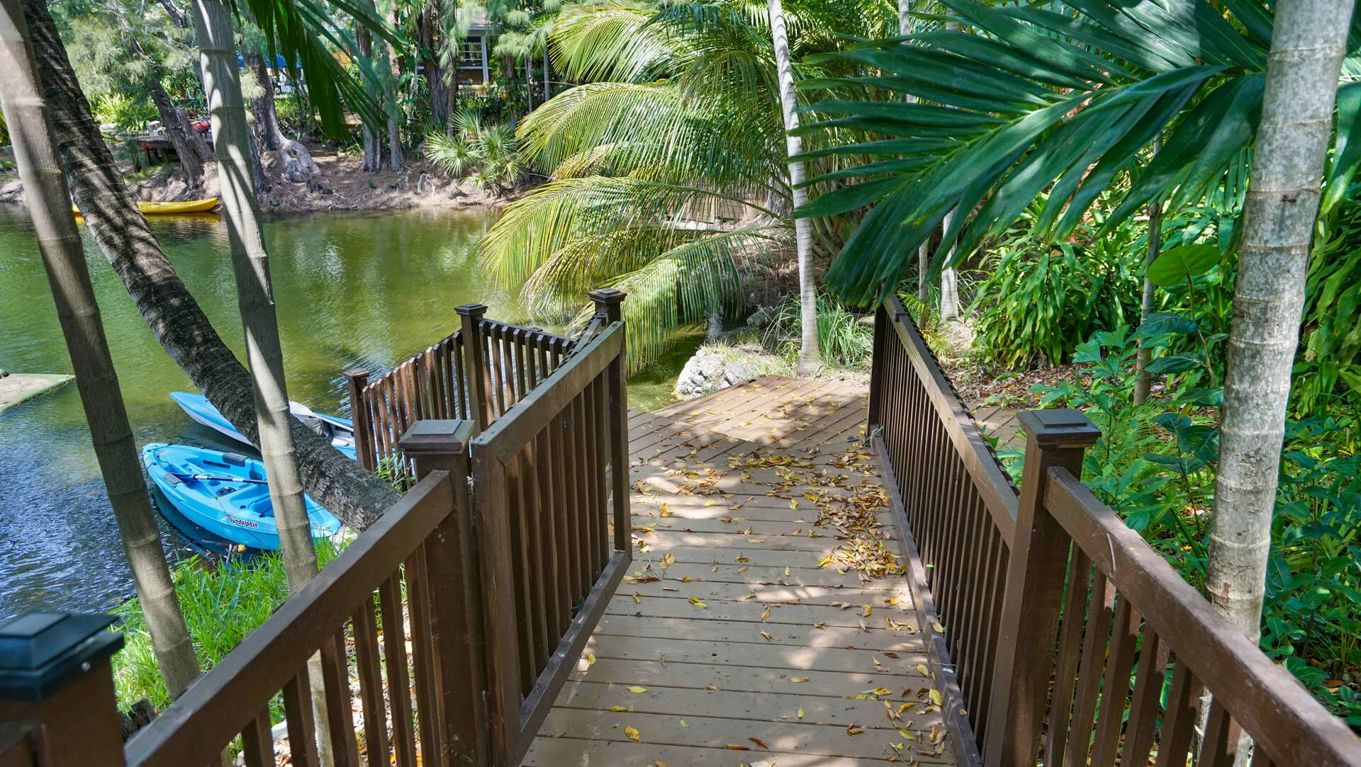 Wood-finish walkway featuring dark wood railings and integrated lighting, leading to a natural waterway