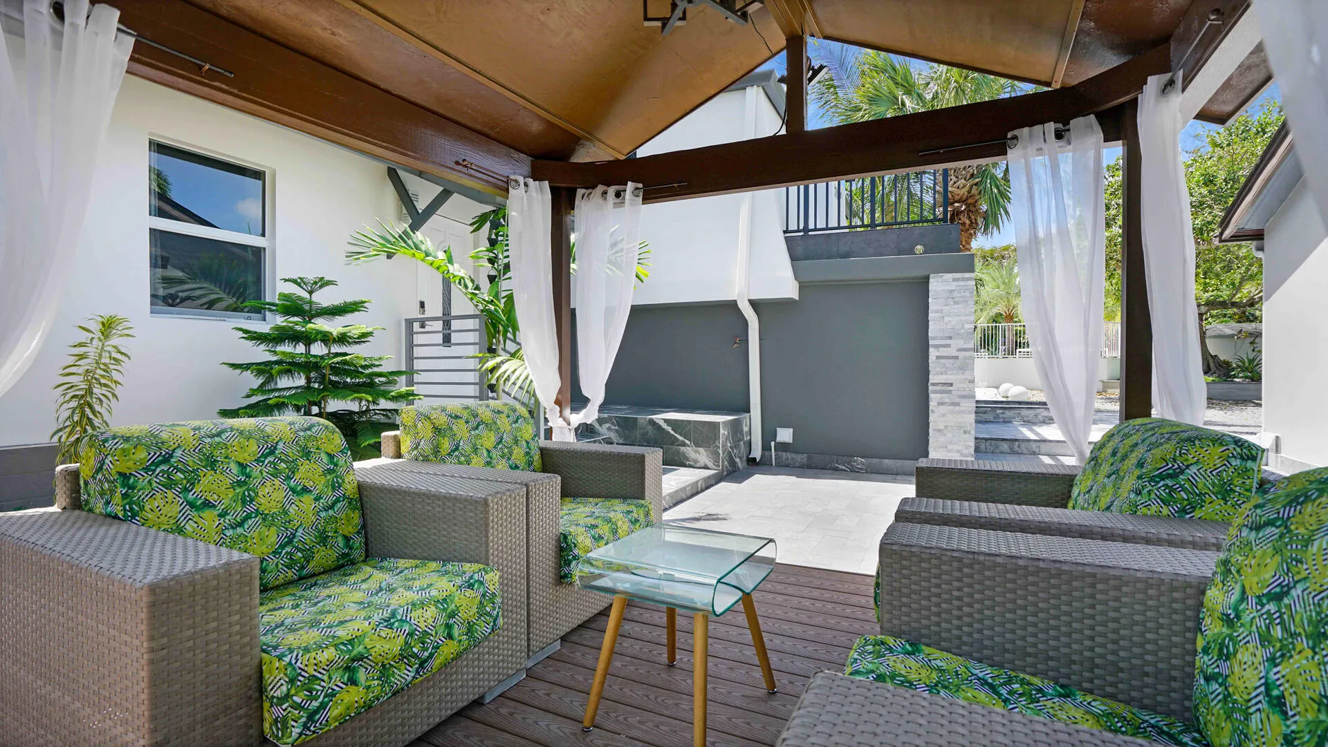 Covered outdoor living area featuring a wood-finish ceiling, exposed beams, and white sheer drapery