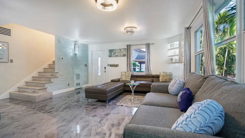 Living area featuring metallic epoxy flooring and a prominent staircase with light-toned treads