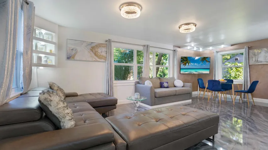 Bright living area featuring reflective flooring, recessed lighting, and built-in shelving with accent lighting