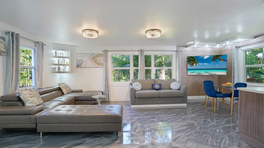 Open-concept living space featuring high-gloss marbled flooring, recessed lighting, and multiple windows