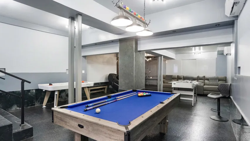Recreational room featuring a blue felt pool table, dark flooring, and a multi-light fixture