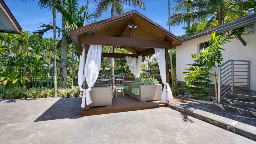 Wood-finish gazebo with a pitched roof and sheer white curtains, set on a raised deck