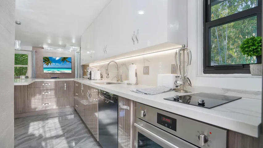Contemporary kitchen featuring white high-gloss upper cabinetry and wood-finish lower cabinetry, complemented by a stone countertop with an integrated sink and an induction cooktop