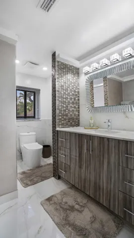 Contemporary vanity with wood-grain cabinetry, a white countertop, and an undermount sink