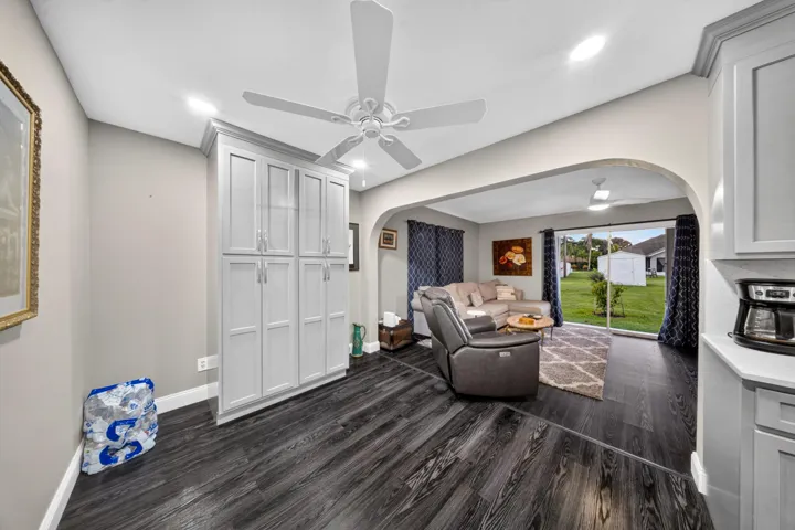 Wood-finish flooring throughout, featuring a tall built-in storage cabinet with white shaker-style doors and chrome hardware