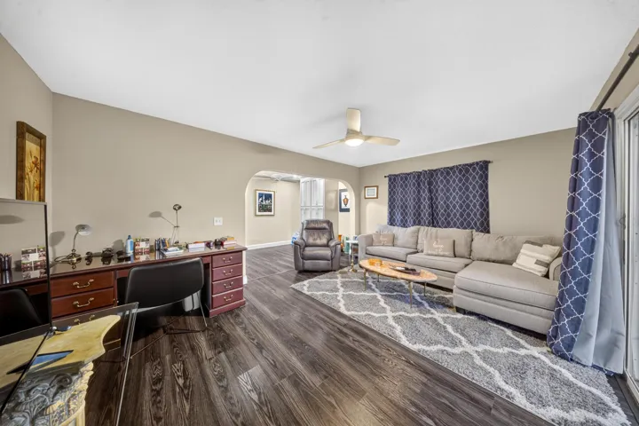 Spacious room featuring wood-finish flooring, a contemporary ceiling fan, and an arched doorway leading to an additional area