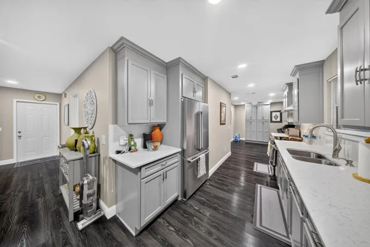 Galley kitchen featuring grey shaker-style cabinetry, light-toned countertops, and stainless steel appliances