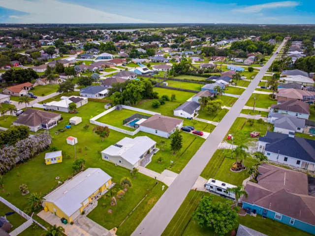 Aerial perspective showcasing a residential neighborhood with single-story homes and expansive green lawns
