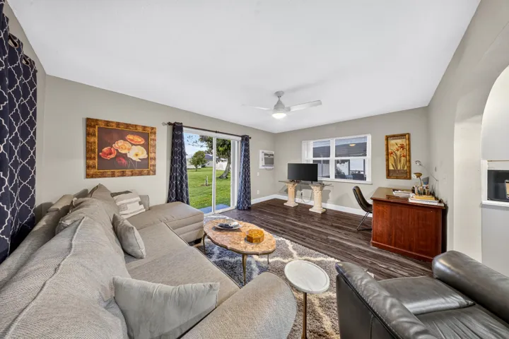 Spacious interior featuring wood-finish flooring, a contemporary ceiling fan, and sliding glass doors leading to an expansive green space