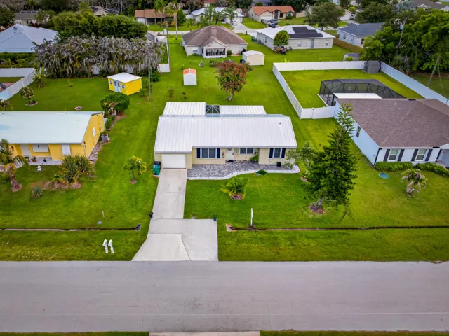 Single-story residential property featuring a metal roof, attached garage, and a concrete driveway
