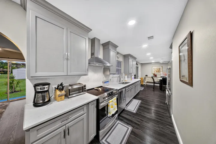 Galley kitchen featuring gray cabinetry, light-toned countertops, and dark wood-finish flooring