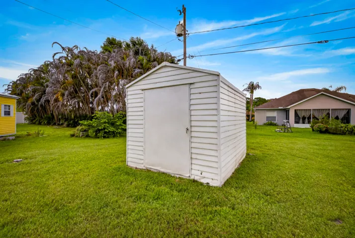 White storage shed featuring horizontal siding and a single entry door