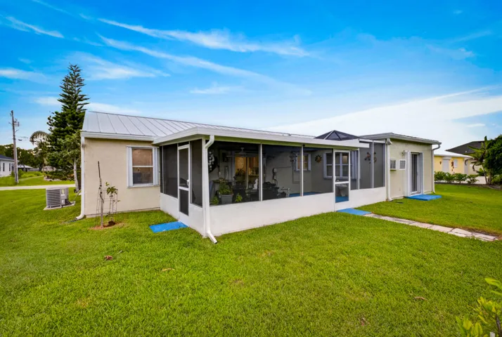 Expansive green lawn with a screened patio featuring a metal roof