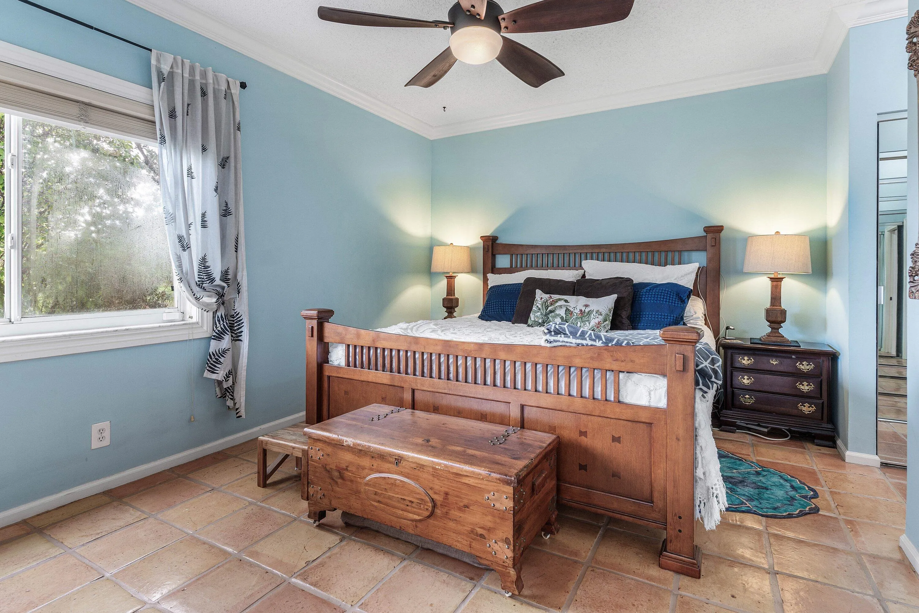 Spacious room featuring tile flooring, a large window, crown molding, a ceiling fan with integrated lighting, and light blue wall tones