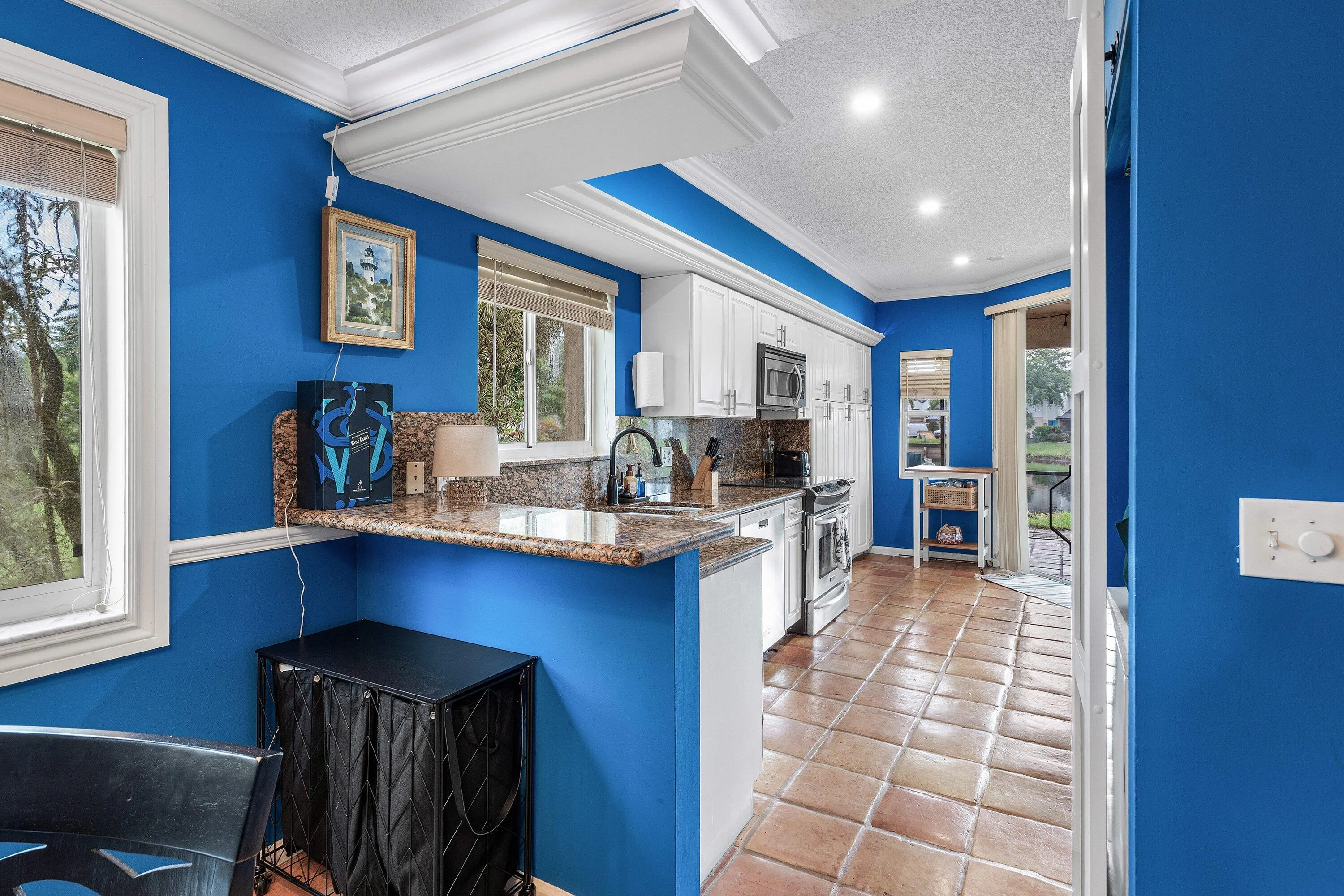 Kitchen featuring white cabinetry, granite countertops, stainless steel appliances, and tile flooring