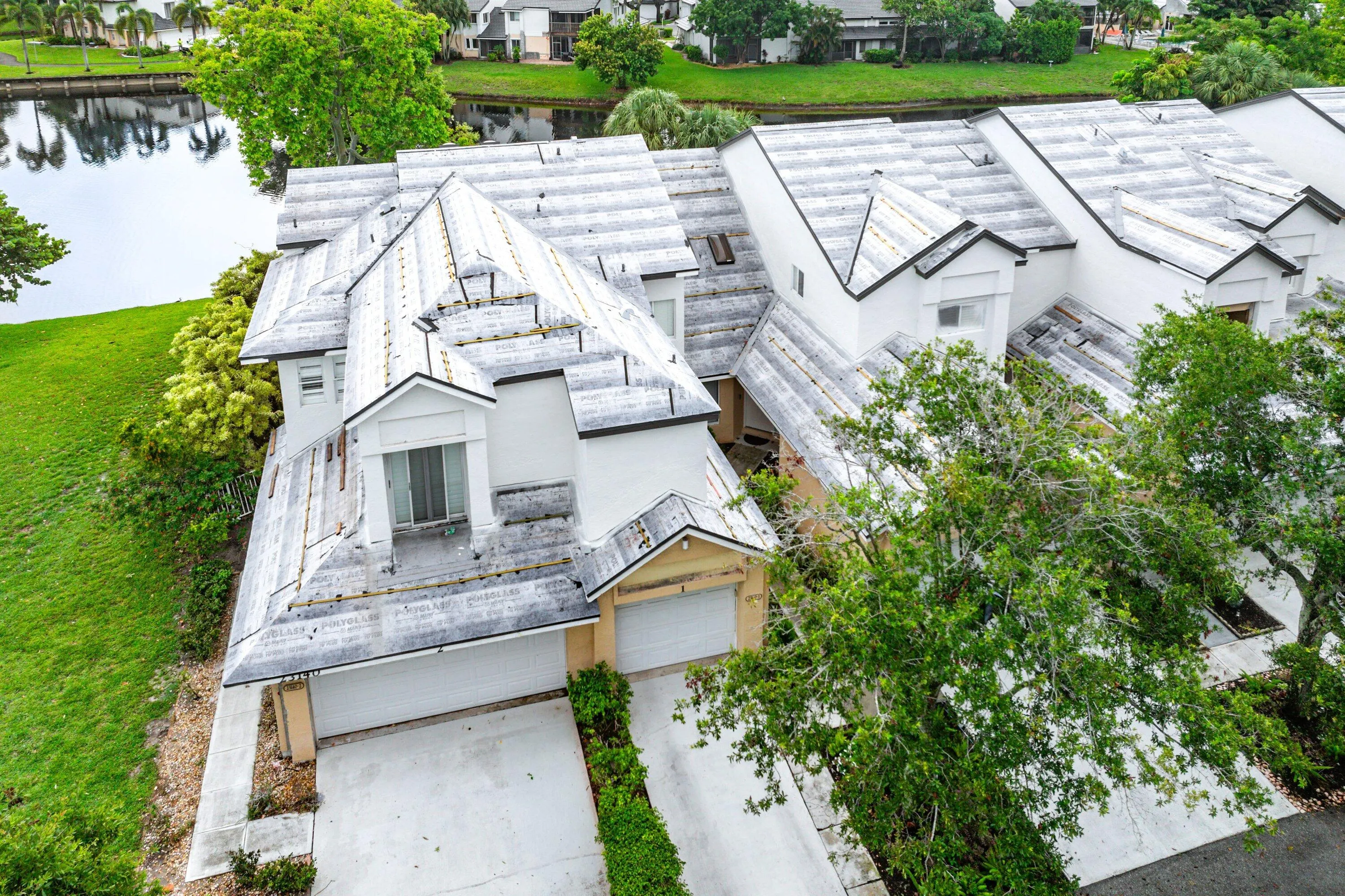 Multi-level townhome featuring a two-car garage, white stucco exterior, and multi-pitched roofing